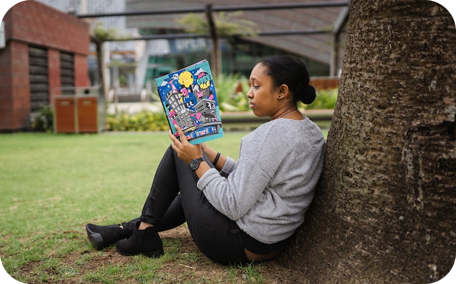 Adolescente lisant un livre dans un parc